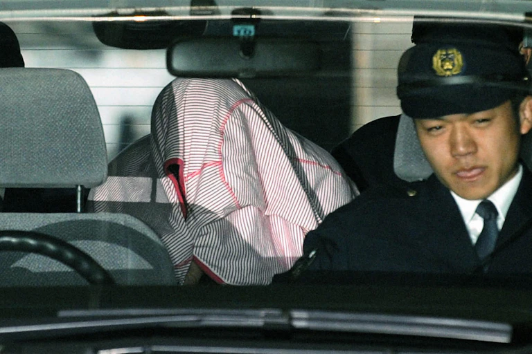 Kanae Kijima hides her face as she is taken from Kawagoe Police Station in February 2010.