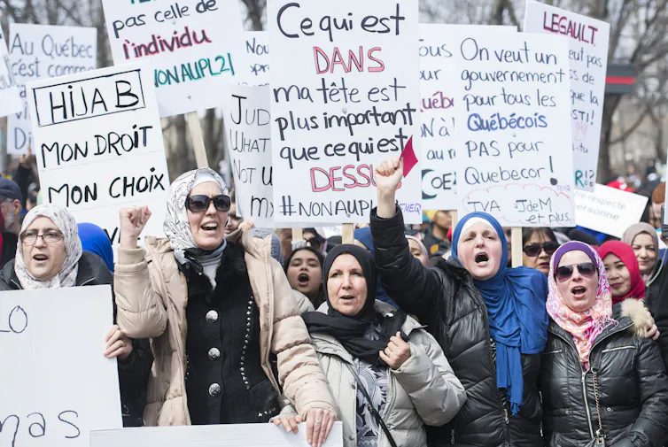 Women wearing hijabs carry signs at a demonstration