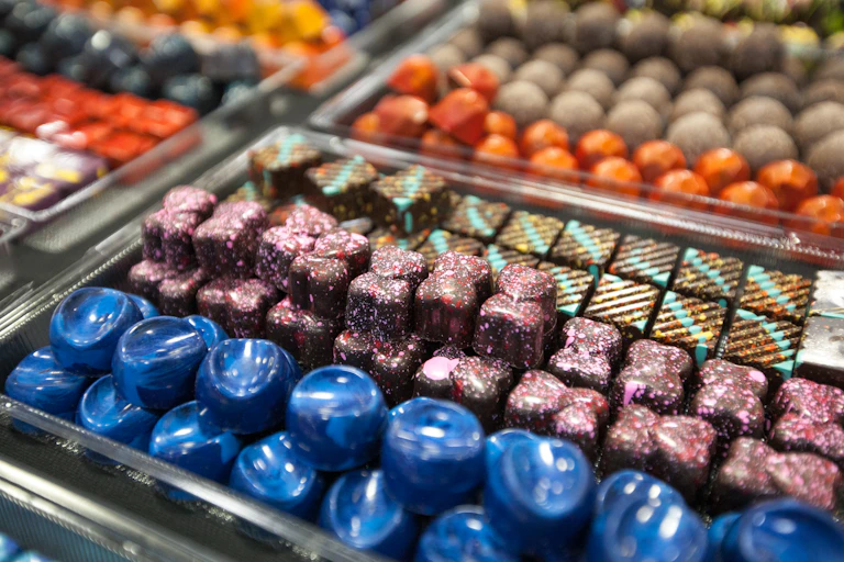 Rows of different types of fancy chocolates in a display case