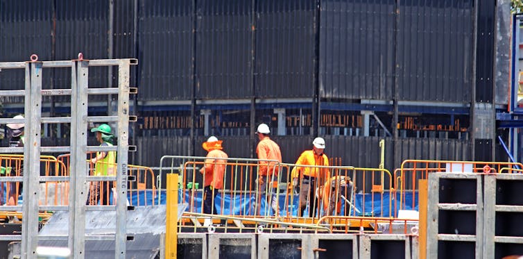 Workers wearing high visibility, orange clothing at a construction site.