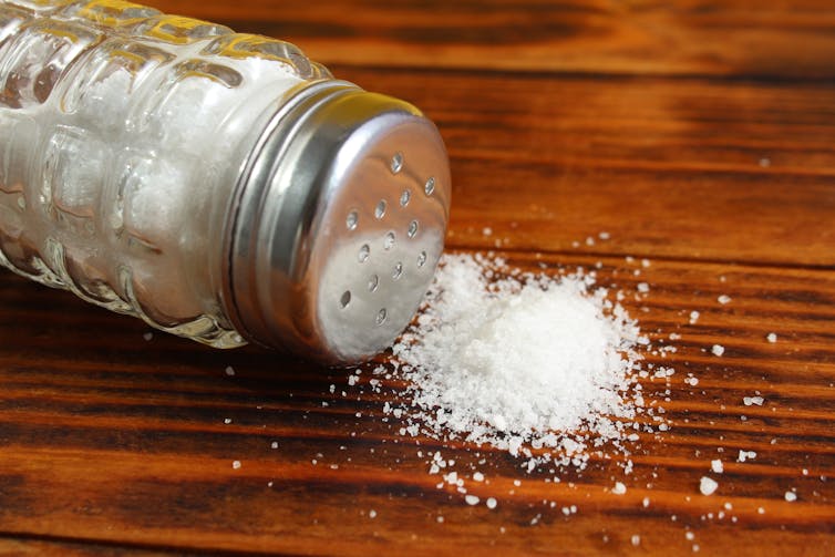 A salt shaker spilling onto a table.