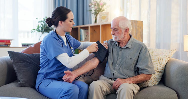 A female nurse taking a senior man's blood pressure.