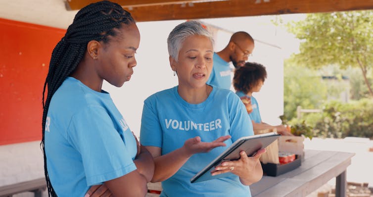 older and younger woman wearing 'volunteer' t-shirts look at clipboard
