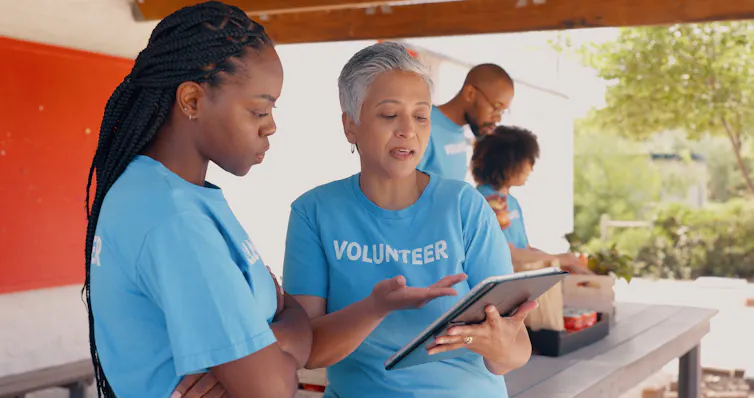 older and younger woman wearing 'volunteer' t-shirts look at clipboard