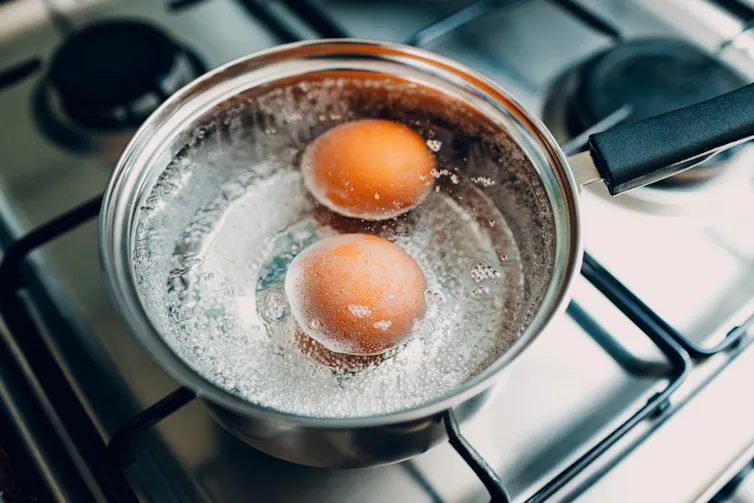 Des œufs dans de l’eau bouillante dans une casserole sur une cuisinière à gaz