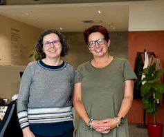 The Conversation editors Victoria Thieberger and Alison Carabine standing side by side in The Conversation offices