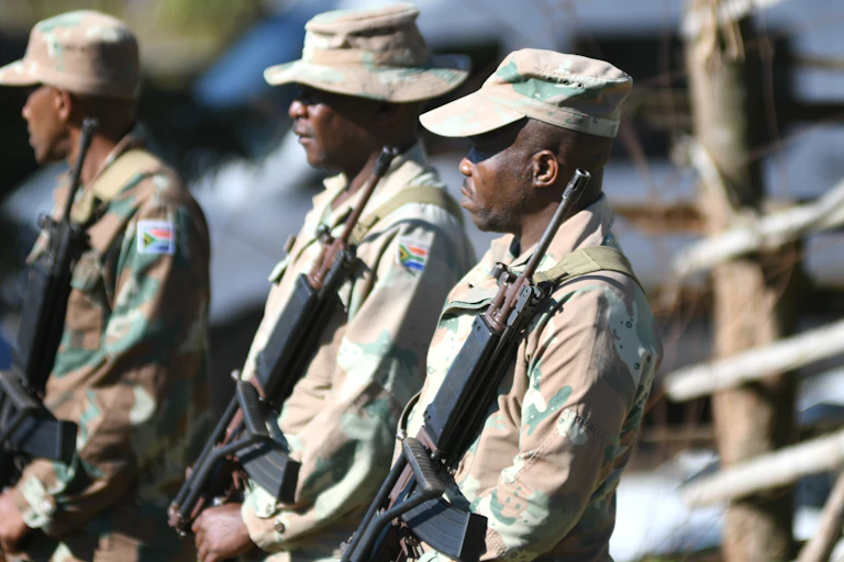 Three SANDF soldiers carrying rifles.