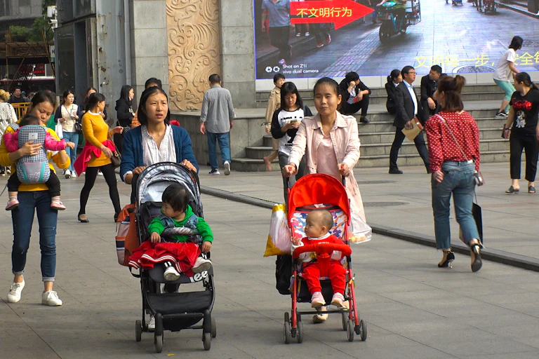 Trois femmes en Chine l'une avec un bébé dans un porte-bébé et deux autres avec un enfant une poussette