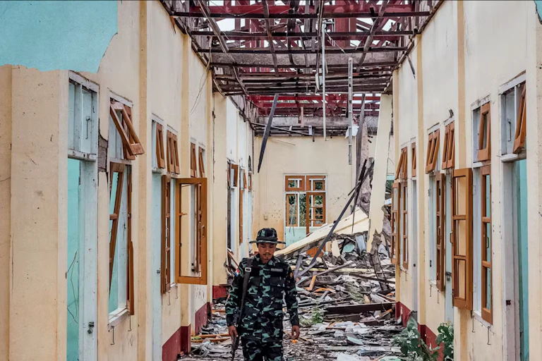 Un soldat marche dans un bâtiment détruit.