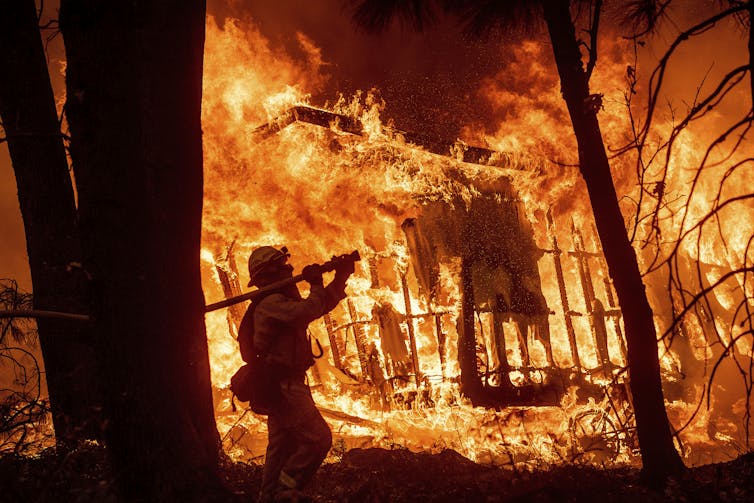 California wildfires drive scholars to take into consideration the connections between STEM and society 1 A fireman walks in front of a house engulfed in flames.
