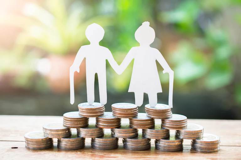 Paper cutout of older couple standing on a stack of coins
