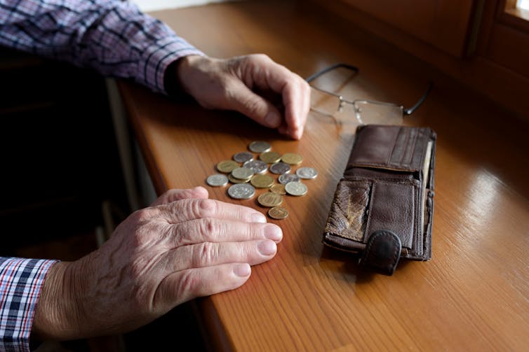 Elderly man's hands putting coins in wallet