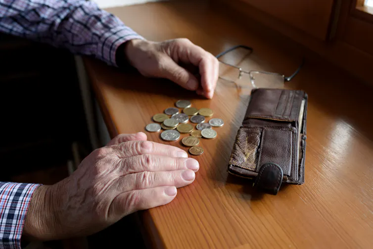 Elderly man's hands putting coins in wallet