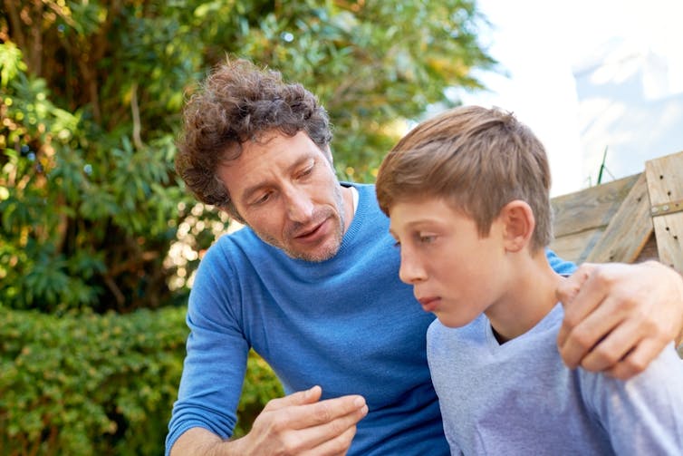 Parents are talking with son/daughter outside, a hand on the child's shoulder
