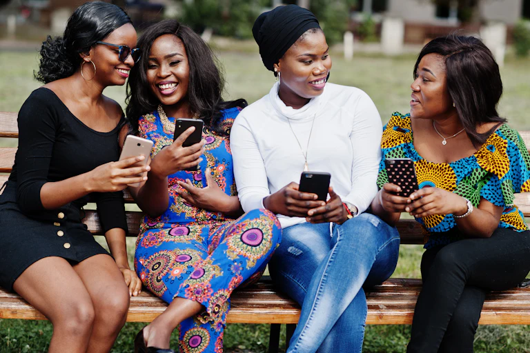 Des jeunes femmes noires discutent entre elles en consultant leurs smartphones.