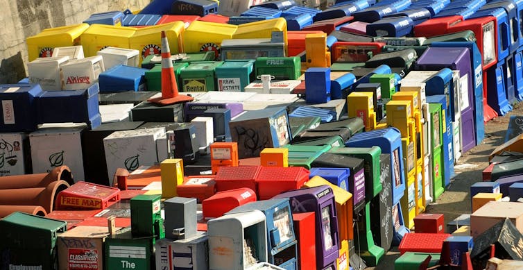 a photo of more than 50 empty newspaper bins in disarray