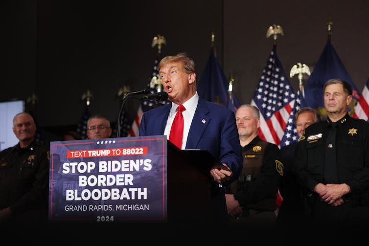Donald Trump speaks in front of a lecturn.