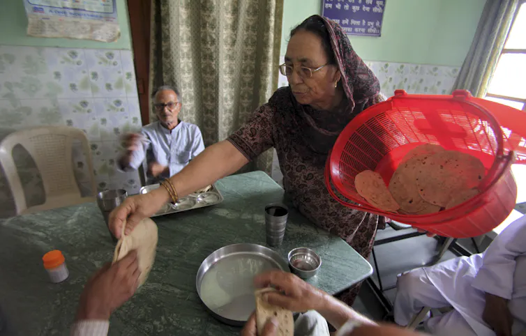 A woman hands slices of flatbread to people seated around a table