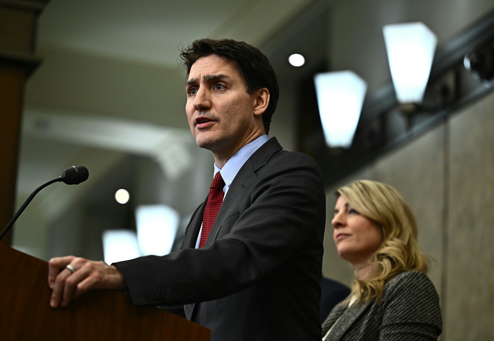 A dark-haired man speaks in front of a lectern with a microphone.