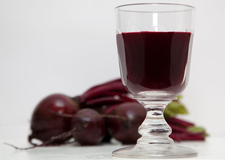 A glass of beet juice with beets in the background.