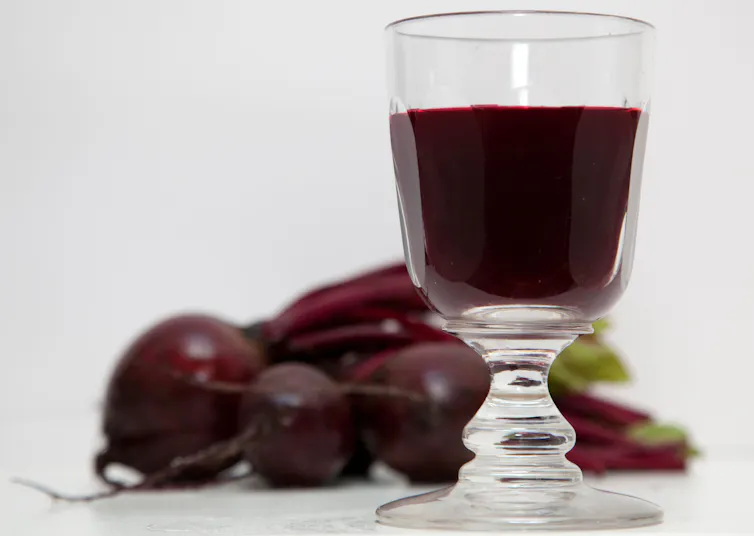 A glass of beetroot juice with beetroots in the background.