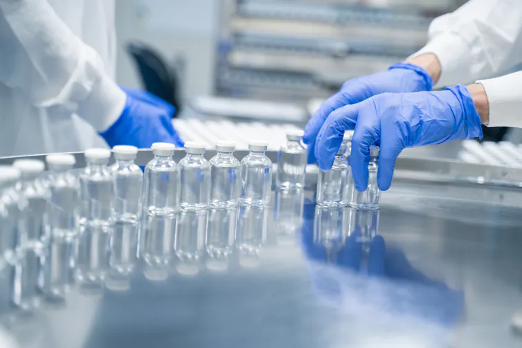Detail of hands working in pharmaceutical factory manufacturing sterile bottles