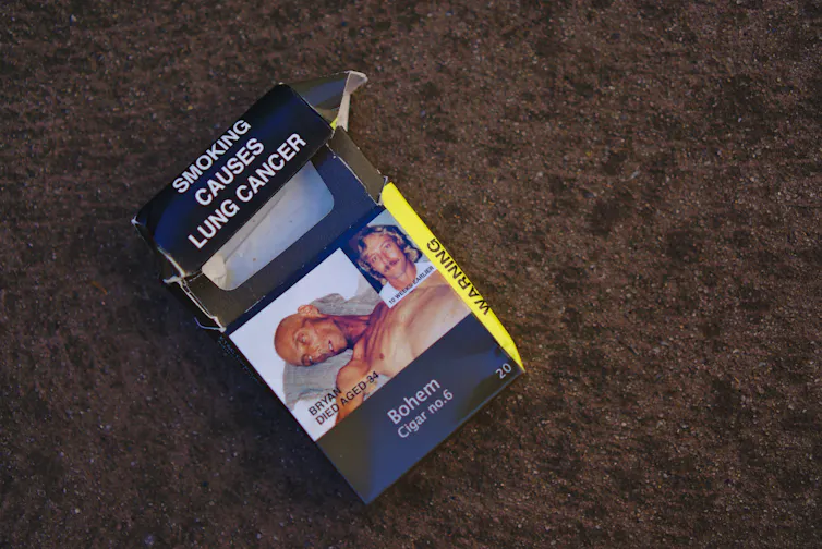 A used cigarette packet on the ground reads