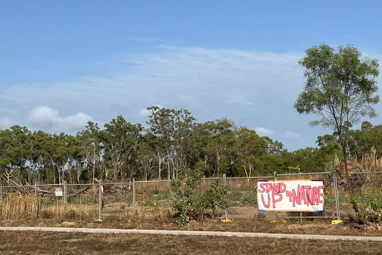 A sign reading 'stand up 4 nature' is attached to a temporary fence around bushland to be cleared at Lee Point (Binybara) in the NT.