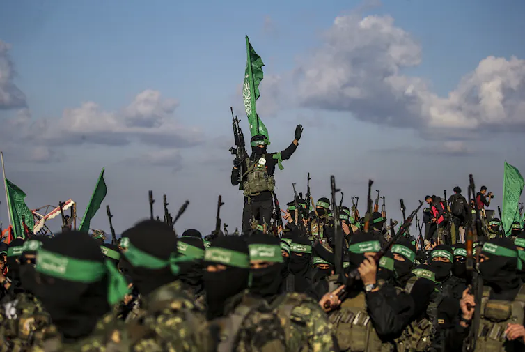 Hamas fighters wearing black face coverings and carrying guns.
