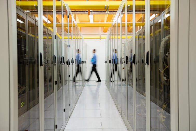 Man walking between large computer servers