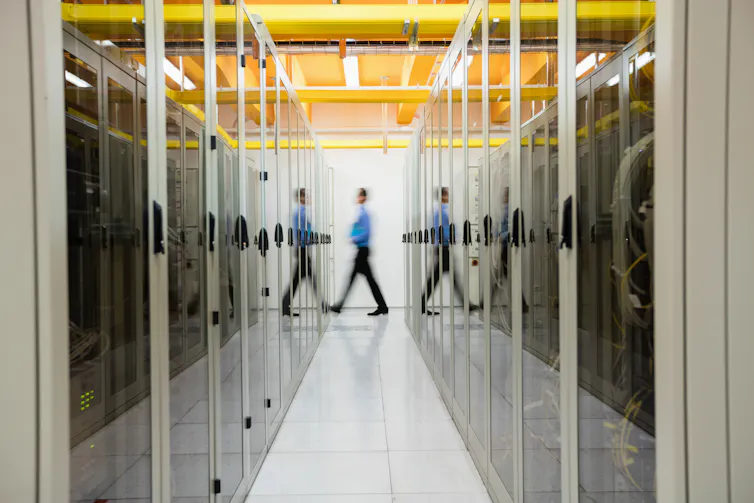Man walking between large computer servers