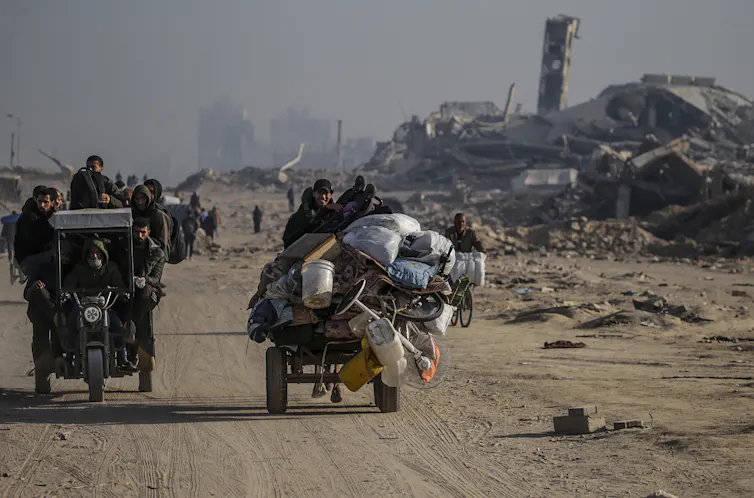 Palestinians on a cart amid damaged buildings.