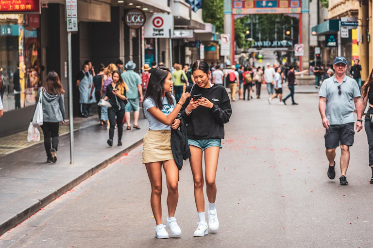 Two young Asian women walk down the street in Chinatown