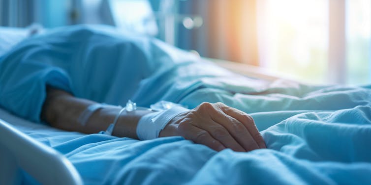 A man is lying in a hospital bed.