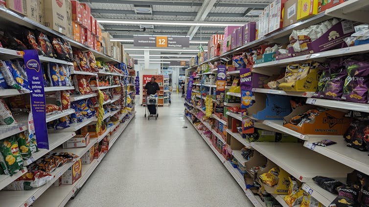 A man pushing a grocery trolley down the crisp aisle in a shop