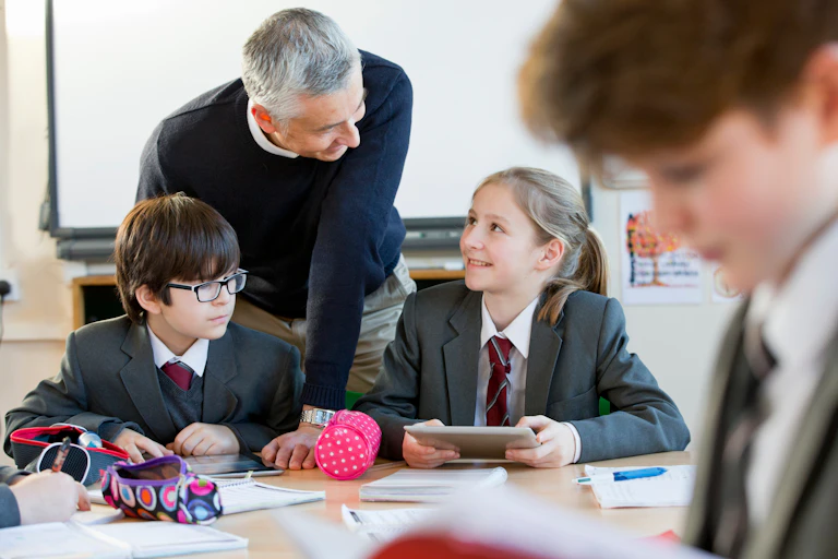 Teacher helping pupils in grey uniform