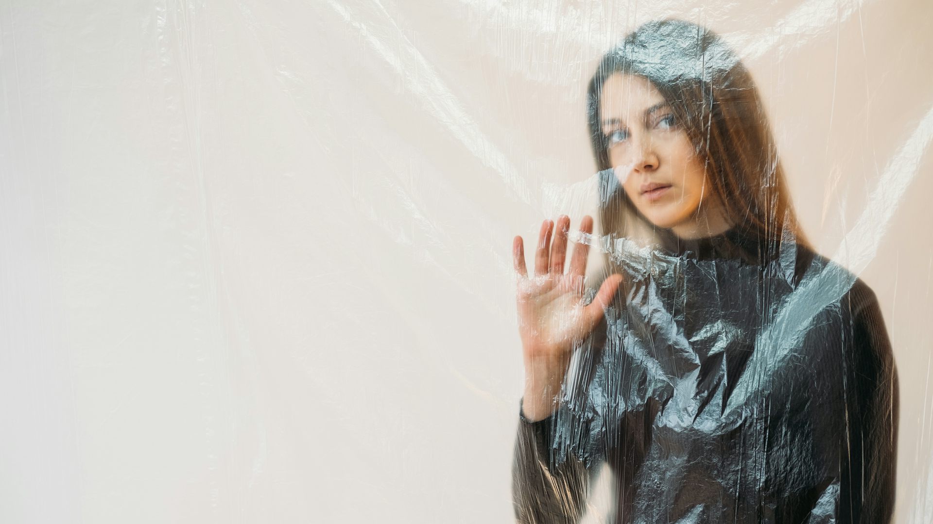 Une femme derrière un rideau transparent n'exprime aucune émotion.