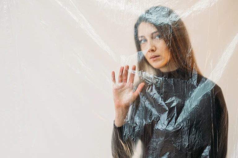 Une femme derrière un rideau transparent n'exprime aucune émotion.