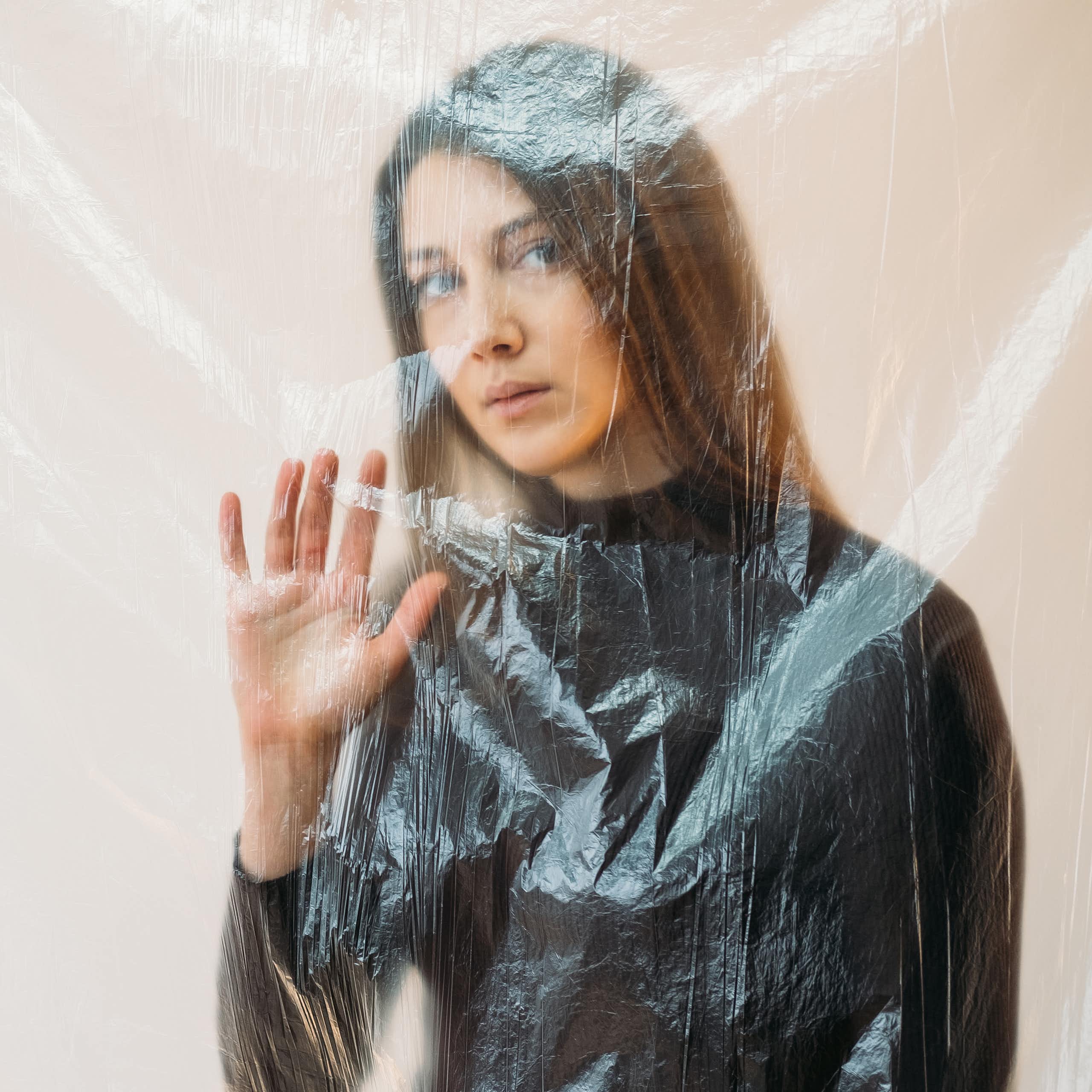 Une femme derrière un rideau transparent n'exprime aucune émotion.