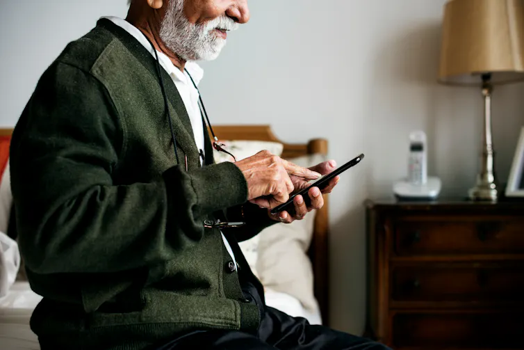 elderly south asian man sitting on a bed