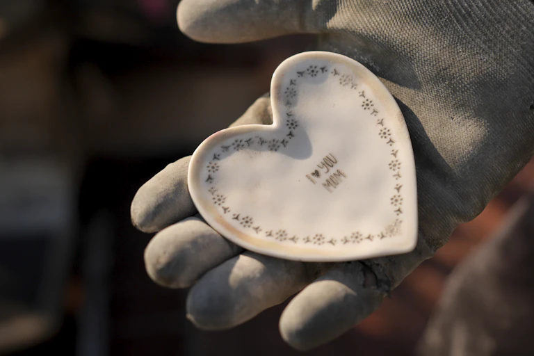 A gloved hand holding a ceramic heart.