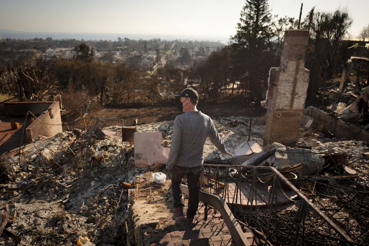 A person walking among burned rubble.