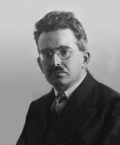 A man in a suit wearing glasses and a tie.
