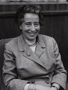 A woman in a buttoned-up jacket with large brooch.