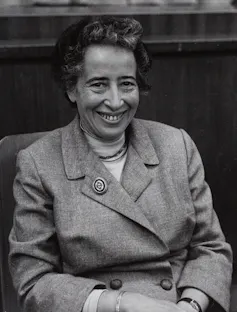 A woman in a buttoned-up jacket with large brooch.