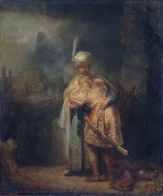 A painting in muted colors of one man with a turban embracing another man who has collapsed on his chest.