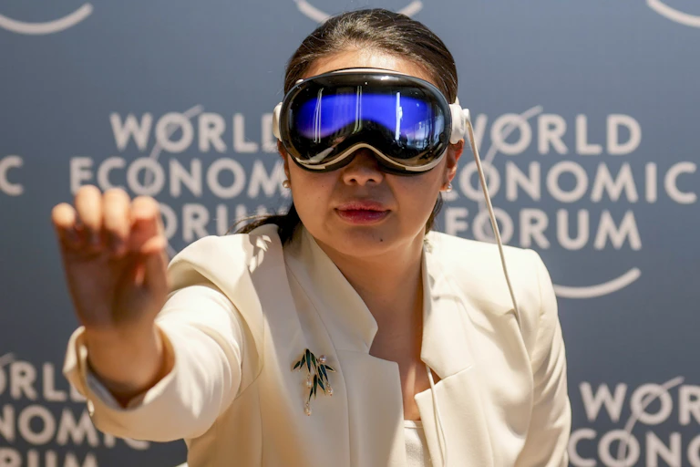 A woman reaches out toward the camera while wearing a pair of virtual reality goggles