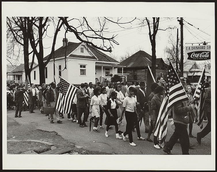 Black people marching with the American flag.