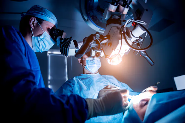 Surgeons performing brain surgery under lights.