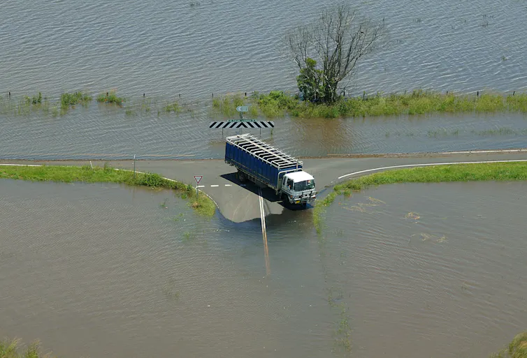 truck stuck on road surrounded by floodwaters